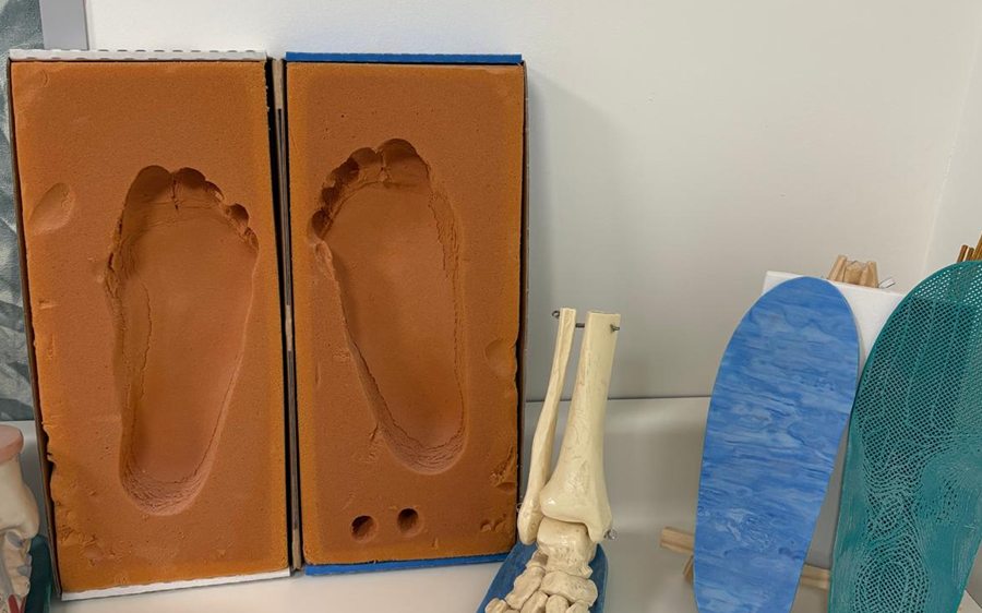 Moldes en espuma de las huellas de los dos pies y modelo anatomico del esqueleto del pie